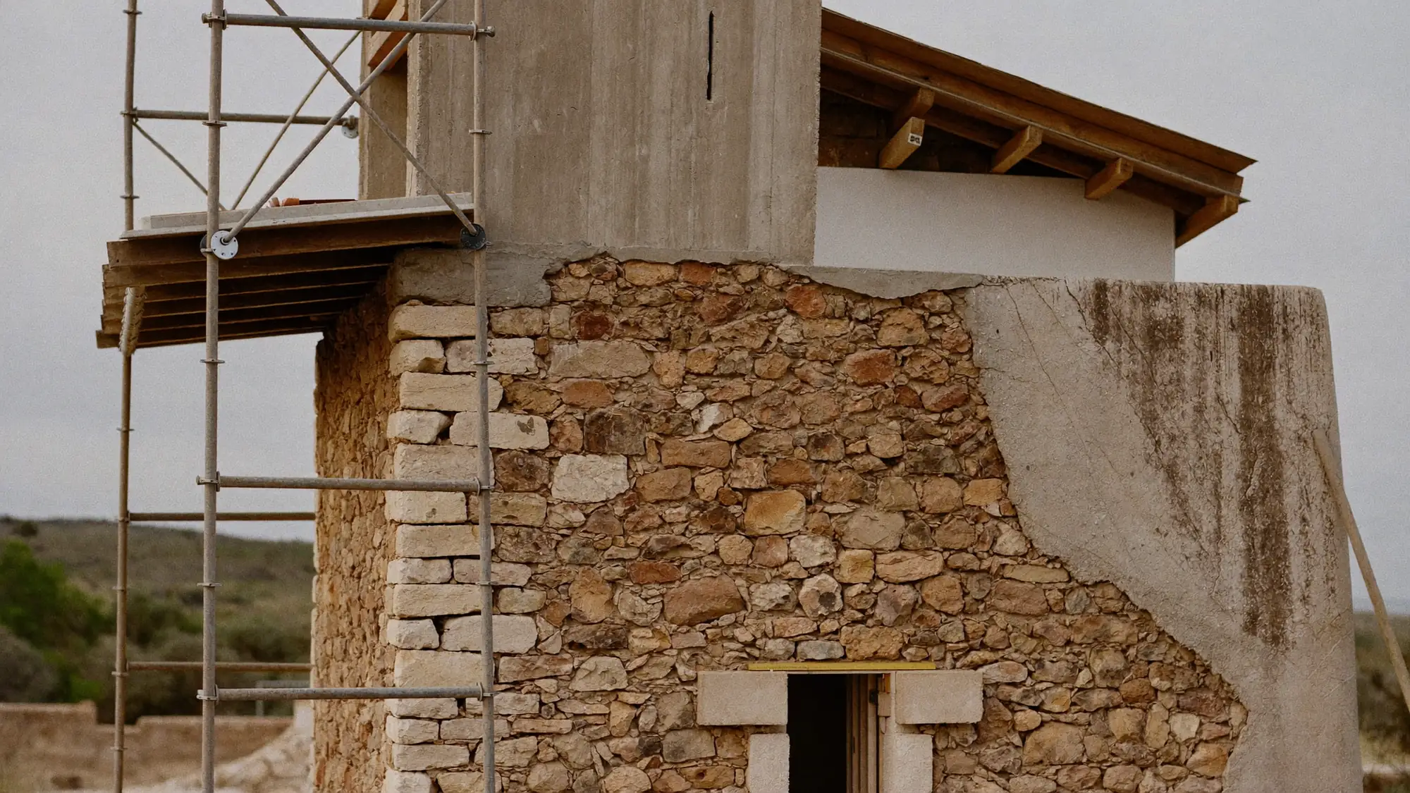 Render orientatiu de la rehabilitació d'un mur de pedra amb bastida.